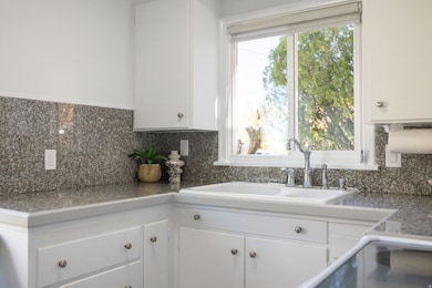 Kitchen featuring tile counters, white cabinetry, backsplash, and range with electric stovetop