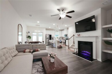 Living room with light wood-style flooring, a ceiling fan, recessed lighting, a glass covered fireplace, and stairs