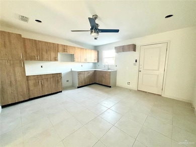 Kitchen with brown cabinetry, a ceiling fan, and light countertops