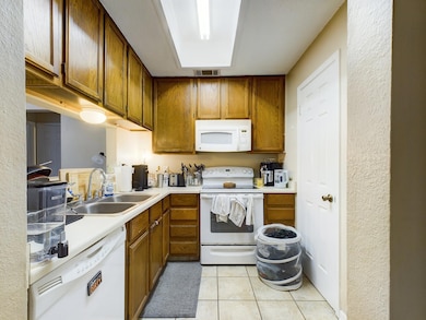 Kitchen featuring white appliances, a sink, brown