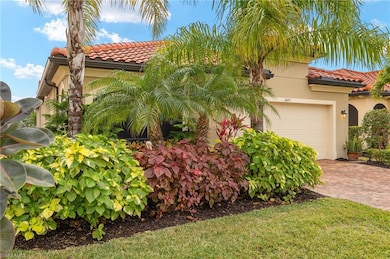 Front of the home with a 2 car attached garage and mature, lush landscaping