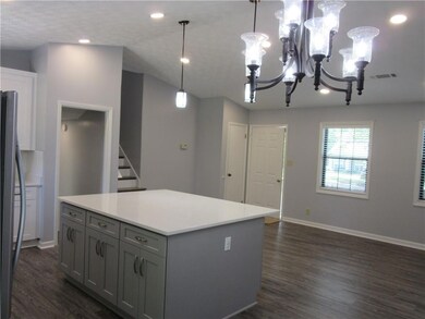 Kitchen featuring gray cabinetry, dark wood finished floors, refrigerator, a chandelier, and light countertops