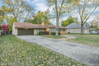 View of front of property featuring a front yard, driveway, an attached garage, and a chimney