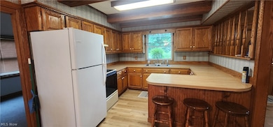 Kitchen with light hardwood / wood-style floors, kitchen peninsula, range with electric cooktop, white refrigerator, and sink