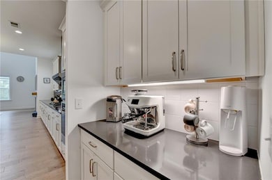Kitchen with tasteful backsplash, white cabinets, 