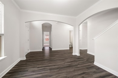 Empty room featuring arched walkways, dark wood-t