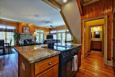 Kitchen featuring wood walls, black electric range, brown cabinetry, french doors, and light stone countertops