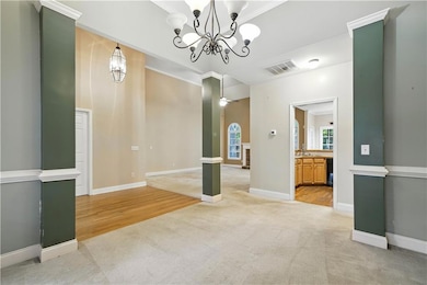 Unfurnished dining area featuring light colored carpet, a chandelier, ornamental molding, and light wood finished floors