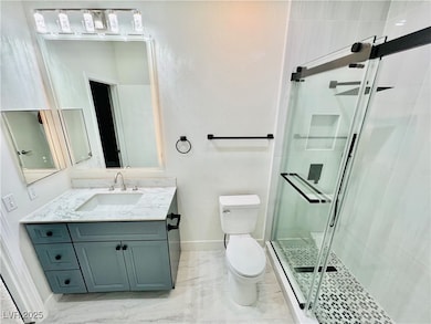 Bathroom featuring vanity, a stall shower, a textured wall, and light marble finish floors