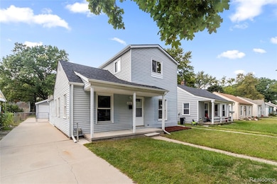 Traditional home with a porch, a shingled roof, an outbuilding, a front lawn, and a garage