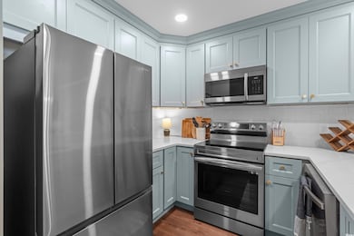 Kitchen featuring stainless steel appliances, light countertops, decorative backsplash, dark wood finished floors, and recessed lighting