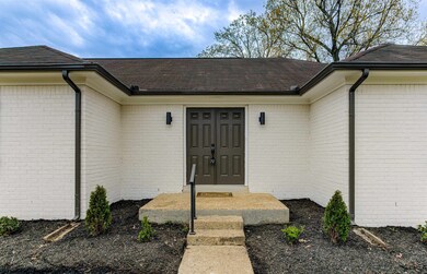 Entrance to property with a shingled roof and bric