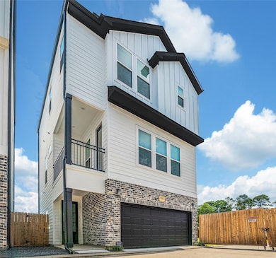 This modern three-story home features a combination of brick and siding exterior, with large windows for natural light. It includes a two-car garage and a balcony.