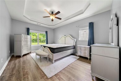 Bedroom with a tray ceiling, wood finished floors, baseboards, and ceiling fan