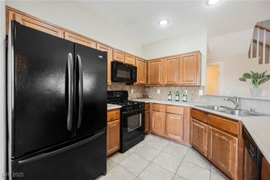 Kitchen featuring black appliances, a sink, light