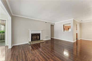 Living room wood finished floors, a fireplace with raised hearth, and crown molding