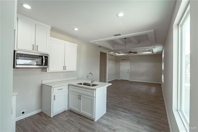 Kitchen with white cabinetry, sink, light hardwood / wood-style flooring, and kitchen peninsula