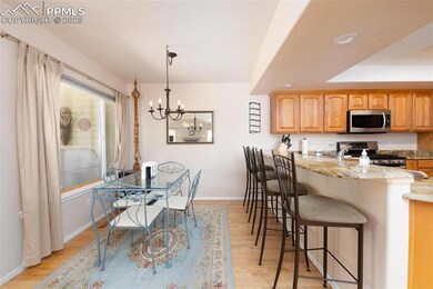 Kitchen featuring appliances with stainless steel finishes, a breakfast bar area, light stone counters, light wood finished floors, and a chandelier