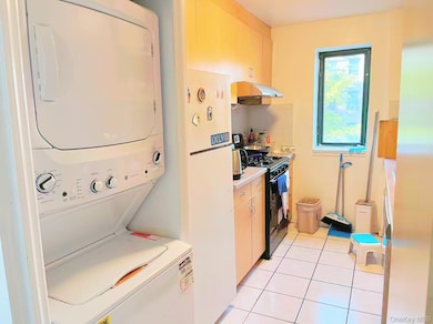 Laundry room with light tile patterned flooring and estacked washer and dryer