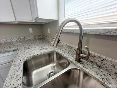 Kitchen view of white cabinetry and light stone counters