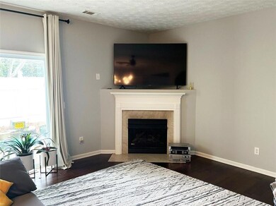 Living room with a textured ceiling, wood finished floors, and a fireplace