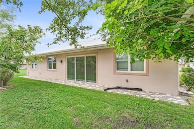 Rear view of property with stucco siding, a lawn,