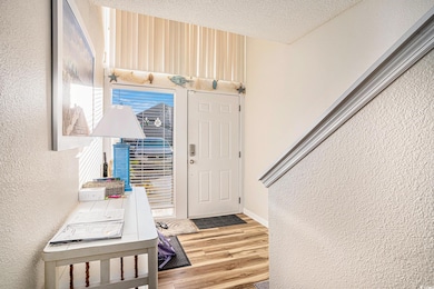 Entrance foyer featuring a textured wall, light wood-style floors, and a textured ceiling