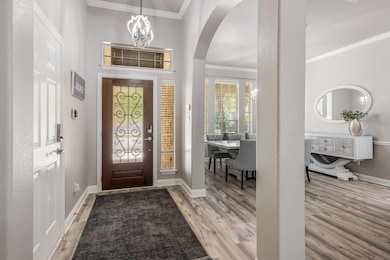 Entrance foyer with crown molding, a chandelier, 