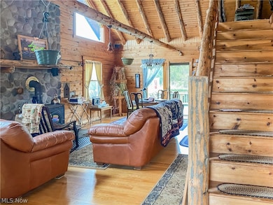 Living room with wood ceiling, wooden walls, a wood stove, and light hardwood / wood-style flooring