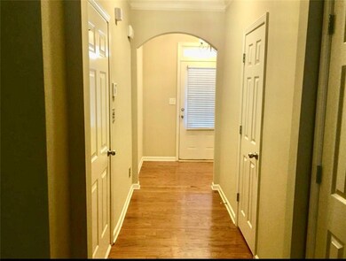 Hallway with crown molding, arched walkways, and light wood-style flooring