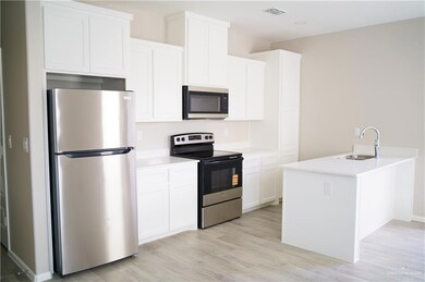 Kitchen featuring stainless steel appliances, a sink, white cabinets, and light wood-style floors