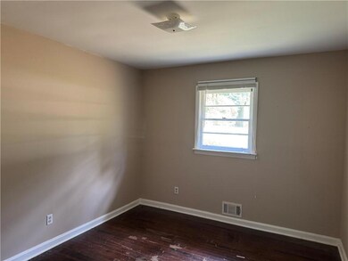 Spare room featuring dark wood-type flooring and baseboards