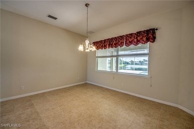 Empty room featuring a chandelier and baseboards