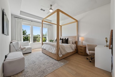 Soft light filters through large windows, highlighting the natural wood tones and layers of cozy textures that make the primary suite shine.