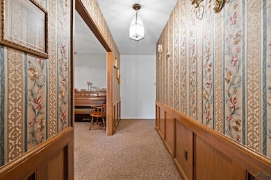 Hall featuring light colored carpet and a textured ceiling