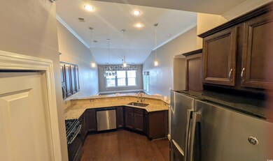 Kitchen with stainless steel appliances, a sink, crown molding, dark brown cabinets, and light stone counters