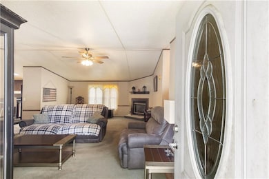 Carpeted living area with a ceiling fan and a glass covered fireplace