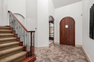 Foyer featuring arched walkways, high vaulted ceiling, and stairs