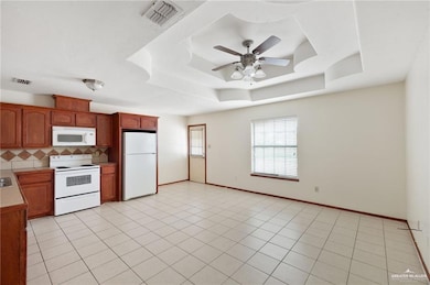 Kitchen featuring visible vents, a ceiling fan, a tray ceiling, tasteful backsplash, and white appliances