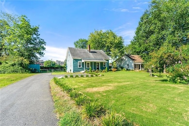View of front of home featuring a chimney, a front lawn, and asphalt driveway
