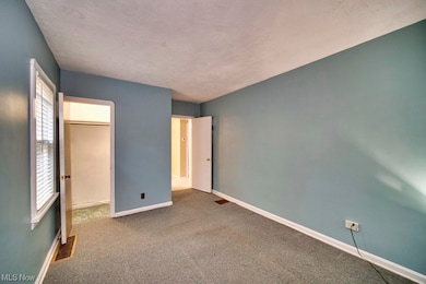 Unfurnished bedroom with a closet, a spacious closet, a textured ceiling, and dark carpet