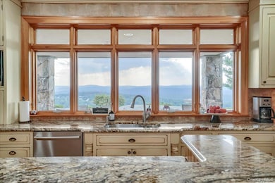 Kitchen featuring sink, stainless steel dishwasher, a mountain view, light stone countertops, and cream cabinetry