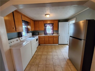 Kitchen with stainless steel appliances, light countertops, washing machine and dryer, brown cabinetry, and a sink