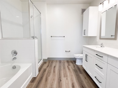 Full bath featuring a bath, vanity, a stall shower, and light wood-style floors