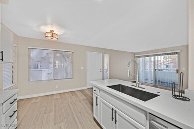 Kitchen featuring a sink, white cabinetry, light c