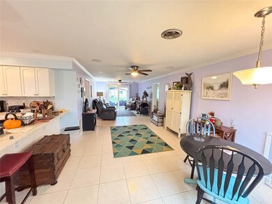 Living area featuring ornamental molding, light tile patterned floors, and ceiling fan
