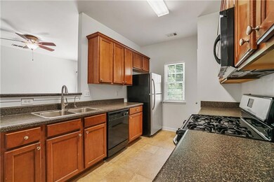Kitchen with black appliances, a sink, dark countertops, and a ceiling fan