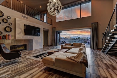 Living room with stairs, a tile fireplace, a towering ceiling, and a chandelier