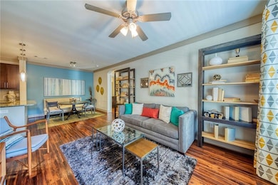 Living room with crown molding, dark wood-type flo