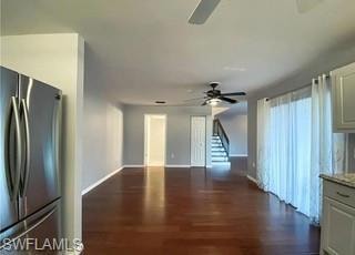 Unfurnished living room/dining room with stairway and dark wood-type flooring